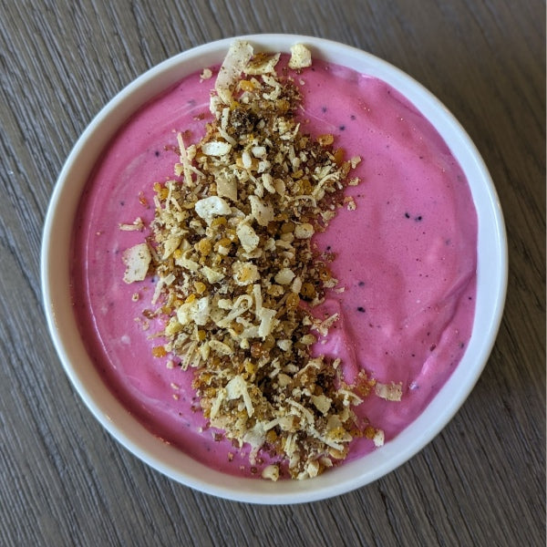 Pink smoothie bowl topped with Babo’s Panjiri on a wooden table