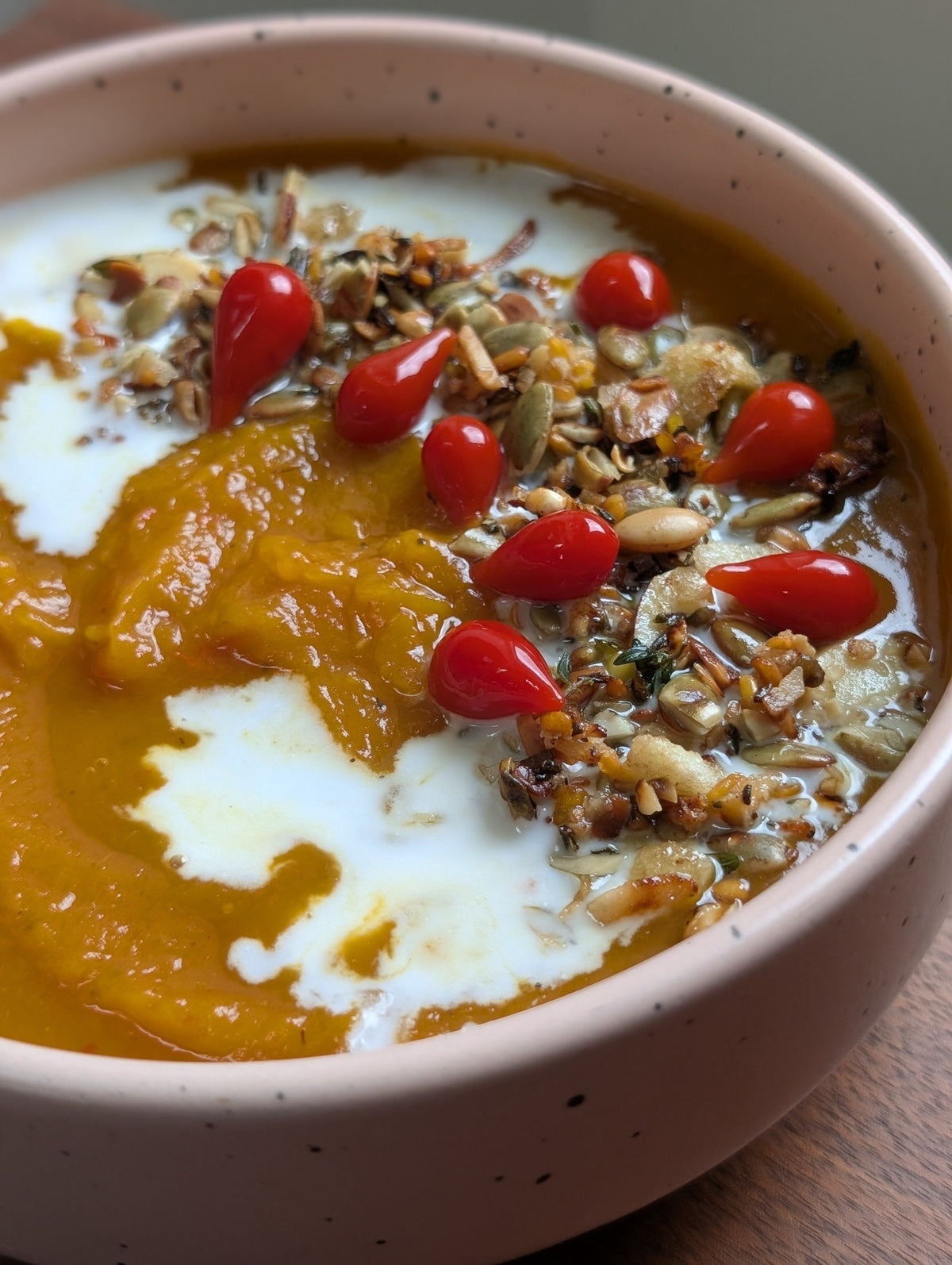 Roasted pumpkin soup topped with yogurt, pickled hot red peppers and a savory Babo's Panjiri garnish with pumpkin seeds and herbs.